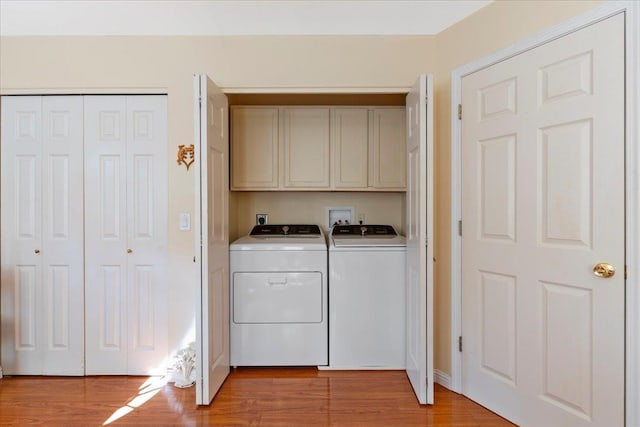 washroom with cabinets, washing machine and clothes dryer, and light hardwood / wood-style floors