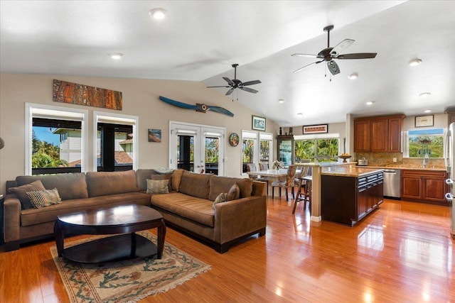 living room with lofted ceiling, french doors, ceiling fan, and light hardwood / wood-style floors