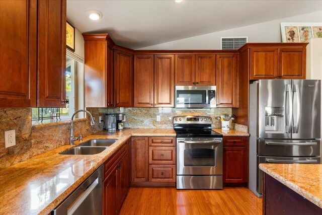 kitchen with sink, backsplash, vaulted ceiling, and appliances with stainless steel finishes