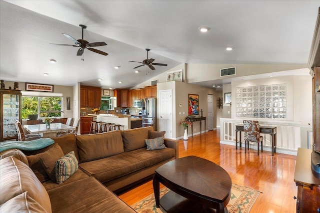 living room with lofted ceiling, light wood-type flooring, and ceiling fan