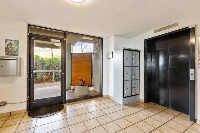 foyer entrance featuring elevator, light tile patterned flooring, and expansive windows