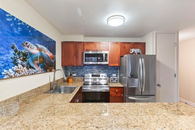 kitchen featuring appliances with stainless steel finishes, light stone counters, tasteful backsplash, and a sink