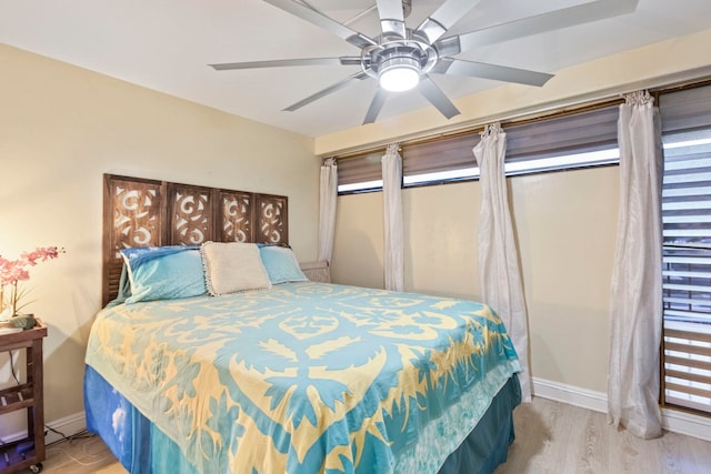 bedroom featuring baseboards, wood finished floors, and a ceiling fan