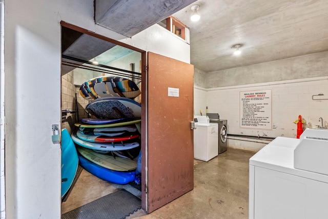 shared laundry area with concrete block wall and separate washer and dryer
