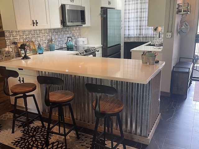 kitchen with white cabinets, tasteful backsplash, stainless steel appliances, and light countertops