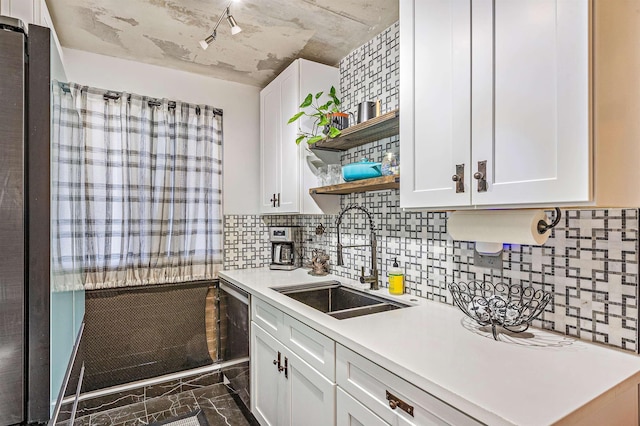 kitchen with white cabinets, a sink, light countertops, open shelves, and stainless steel dishwasher