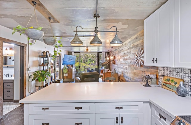 kitchen featuring light countertops, a sink, a peninsula, and white cabinetry