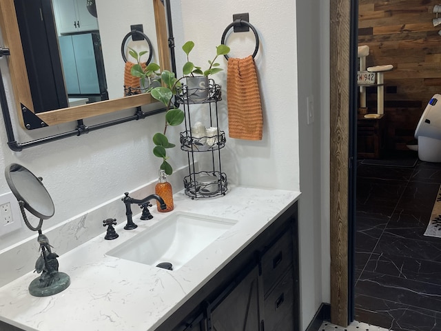 bathroom with marble finish floor, wood walls, and vanity