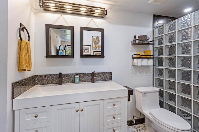 bathroom with a walk in shower, vanity, and toilet