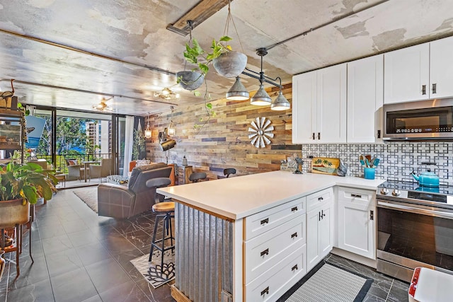 kitchen featuring a peninsula, appliances with stainless steel finishes, open floor plan, and white cabinets