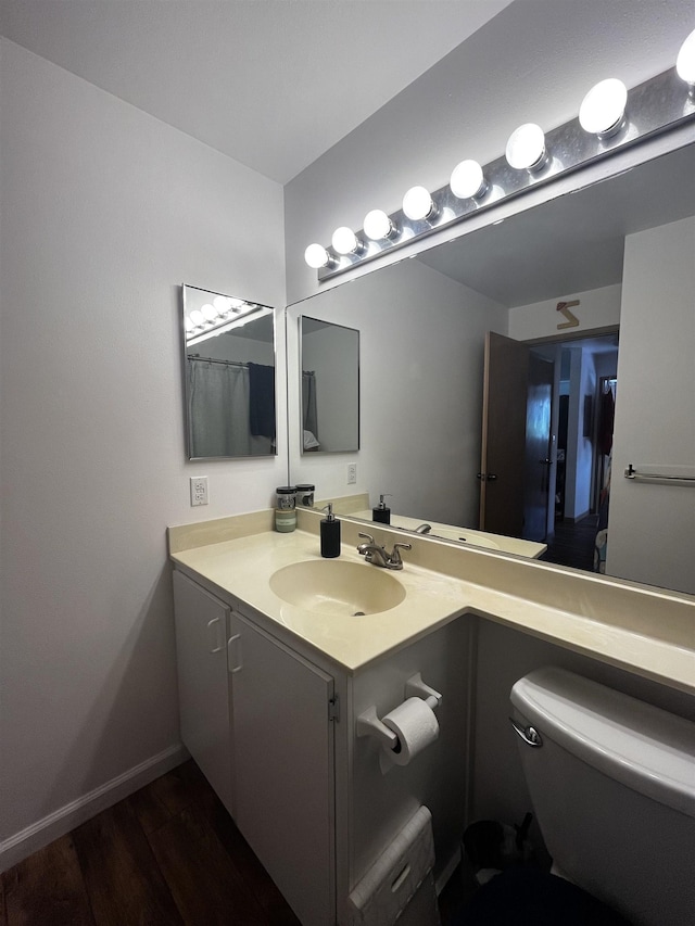 bathroom with hardwood / wood-style flooring, toilet, and vanity