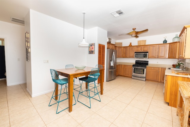 kitchen with light tile floors, appliances with stainless steel finishes, sink, ceiling fan, and pendant lighting