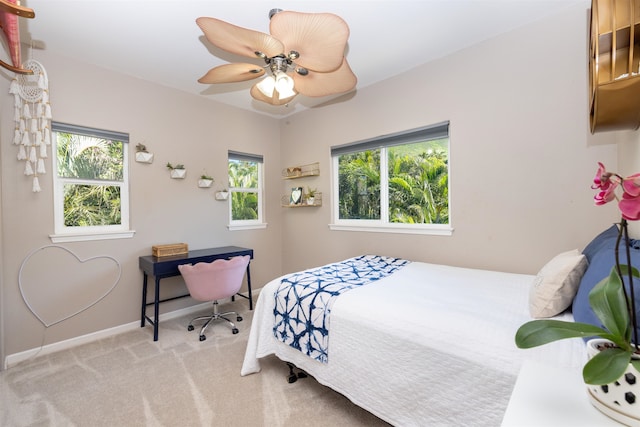 bedroom featuring light colored carpet, ceiling fan, and multiple windows