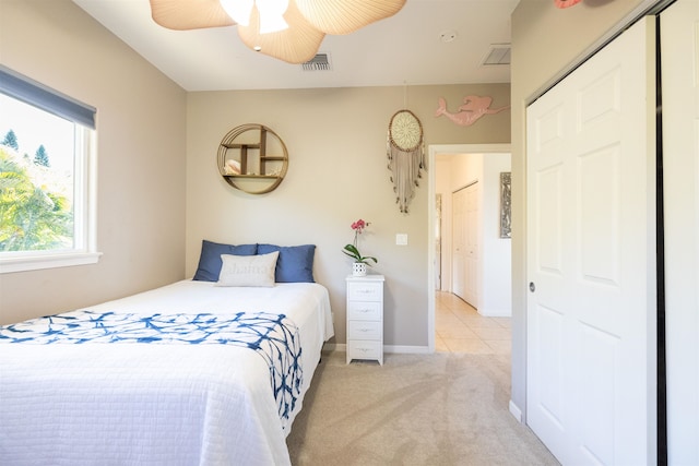 bedroom with ceiling fan, light carpet, and a closet