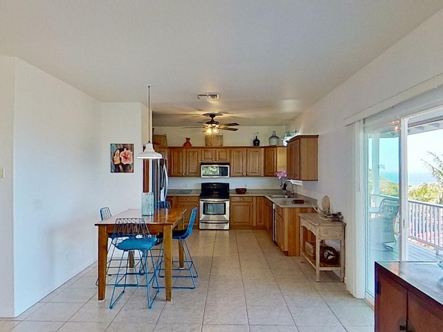 kitchen featuring appliances with stainless steel finishes, ceiling fan, a breakfast bar, light tile floors, and sink