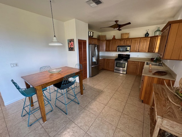 kitchen featuring light tile flooring, pendant lighting, ceiling fan, stainless steel appliances, and sink