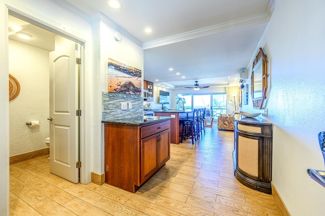 kitchen featuring light hardwood / wood-style floors, dark stone counters, ceiling fan, and ornamental molding