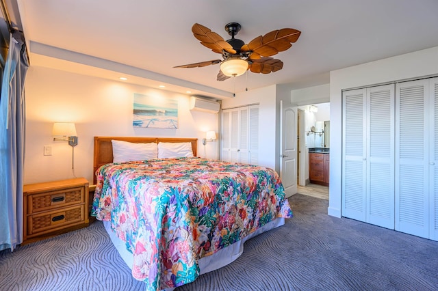 bedroom featuring ensuite bathroom, carpet floors, two closets, ceiling fan, and a wall mounted AC