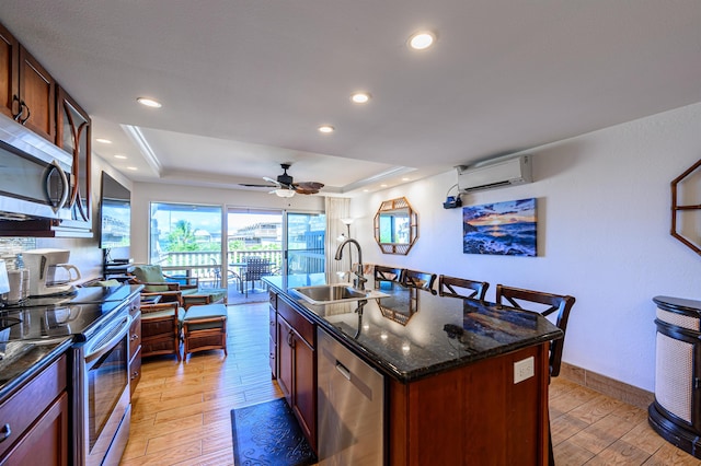 kitchen featuring sink, stainless steel appliances, a raised ceiling, and a kitchen island with sink