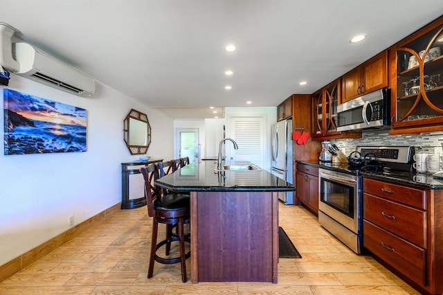 kitchen featuring appliances with stainless steel finishes, sink, a center island with sink, a wall mounted AC, and a breakfast bar area