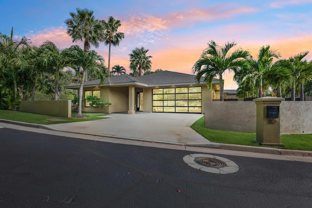 view of front of property with stucco siding, concrete driveway, an attached garage, and fence