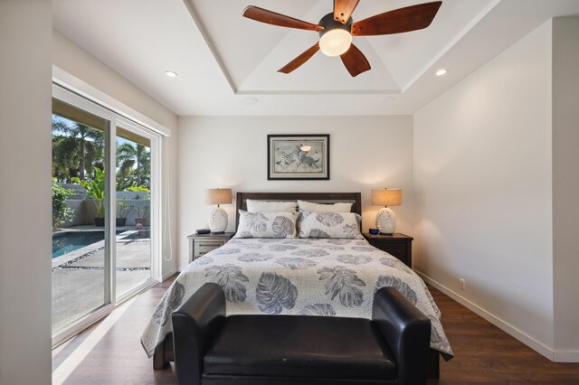 bedroom featuring a raised ceiling, wood finished floors, recessed lighting, baseboards, and access to exterior