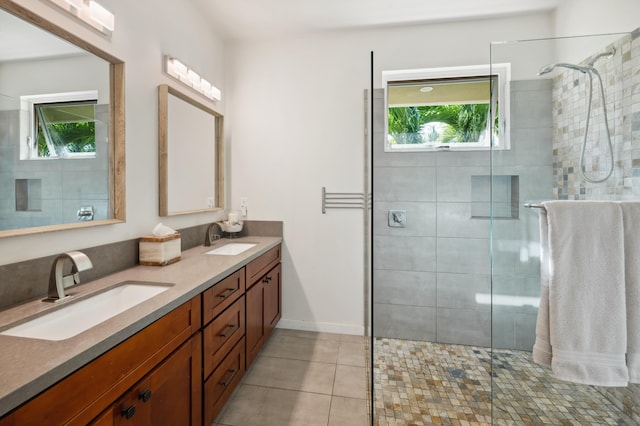 bathroom with tile patterned flooring, double vanity, tiled shower, and a sink