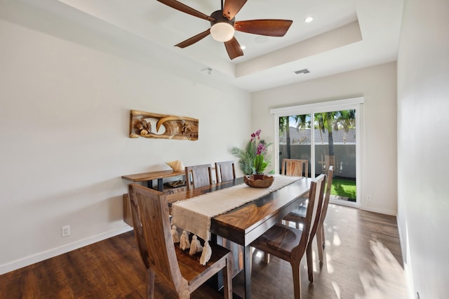 dining space featuring visible vents, ceiling fan, baseboards, wood finished floors, and a raised ceiling