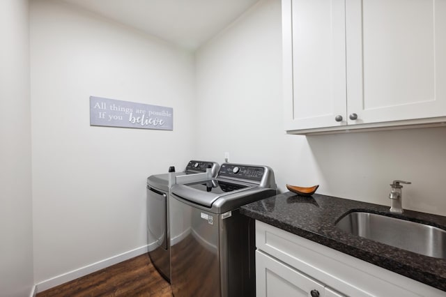 clothes washing area featuring a sink, cabinet space, baseboards, dark wood-style flooring, and washing machine and clothes dryer