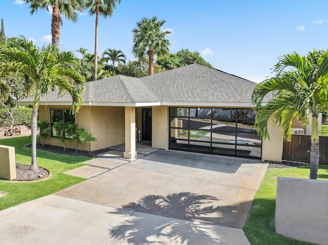 view of front of home with stucco siding, roof with shingles, a front lawn, and fence