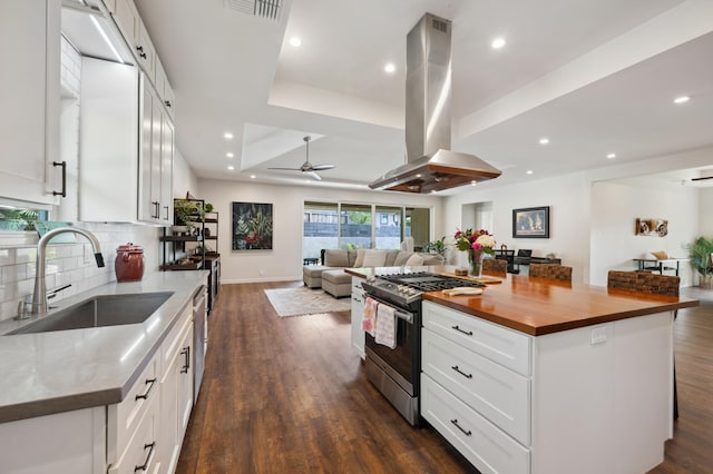 kitchen with visible vents, butcher block counters, appliances with stainless steel finishes, island exhaust hood, and a sink