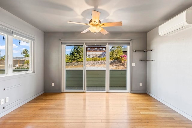 empty room featuring a wall unit AC, ceiling fan, and light wood-type flooring