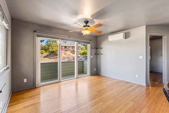 unfurnished room with ceiling fan, a wall mounted air conditioner, and light wood-type flooring