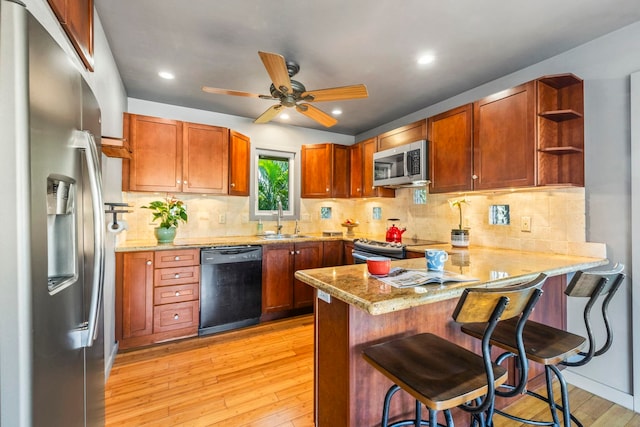 kitchen featuring kitchen peninsula, light wood-type flooring, stainless steel appliances, sink, and a breakfast bar area