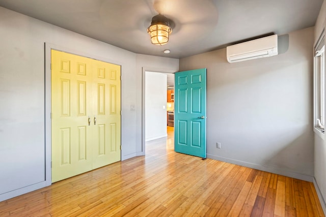 unfurnished bedroom featuring a closet, light hardwood / wood-style flooring, and a wall mounted AC