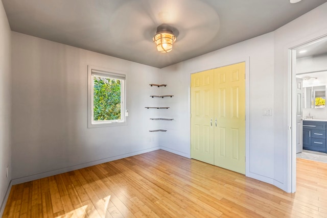 unfurnished bedroom featuring ensuite bath, a closet, and light hardwood / wood-style floors