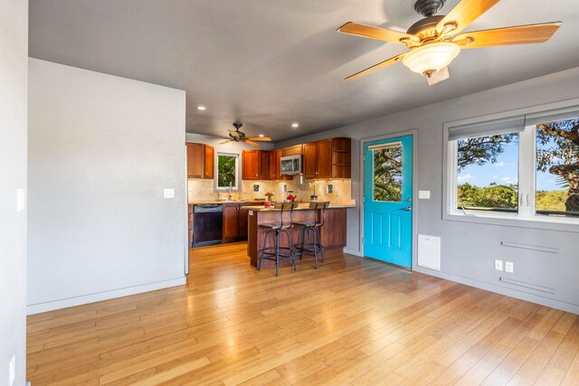 kitchen with kitchen peninsula, a kitchen breakfast bar, light wood-type flooring, tasteful backsplash, and dishwasher