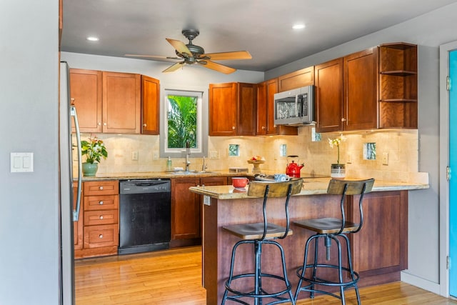 kitchen with dishwasher, sink, a kitchen breakfast bar, light stone counters, and kitchen peninsula