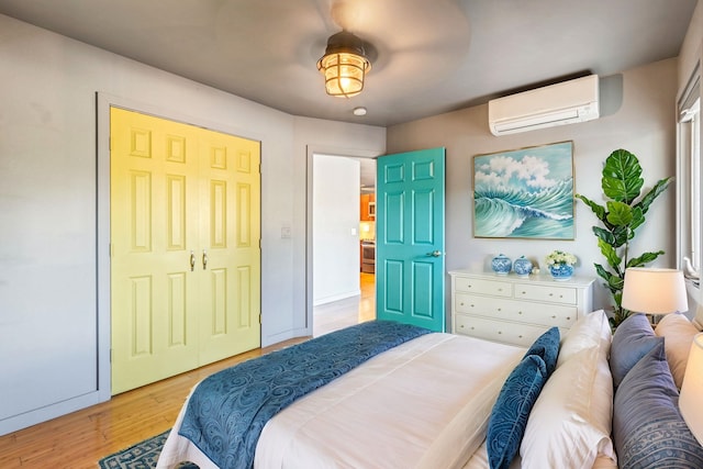 bedroom with an AC wall unit, light hardwood / wood-style flooring, and a closet