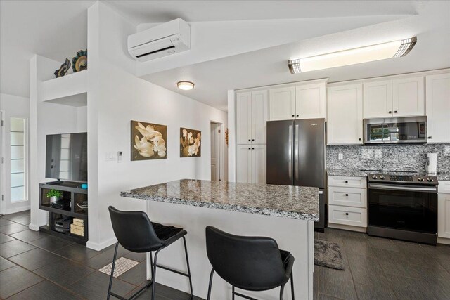 kitchen featuring a kitchen bar, an AC wall unit, light stone countertops, and stainless steel appliances