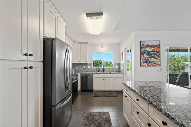 kitchen with plenty of natural light, freestanding refrigerator, backsplash, dishwasher, and a sink