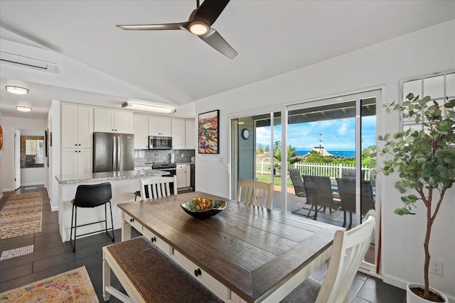 dining room with a wall mounted AC, dark tile patterned floors, lofted ceiling, baseboards, and ceiling fan