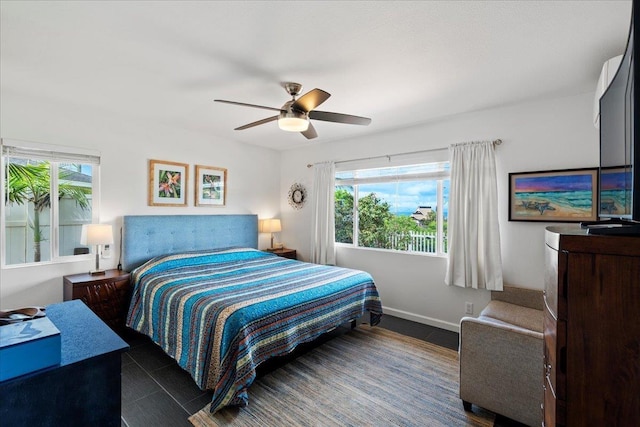 tiled bedroom with baseboards, multiple windows, and a ceiling fan