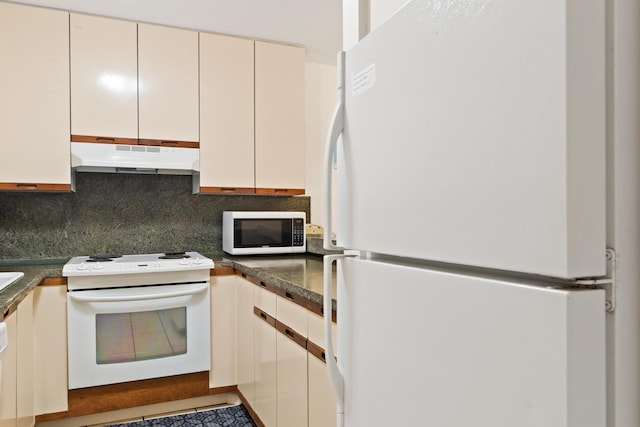 kitchen featuring decorative backsplash, dark countertops, under cabinet range hood, and white appliances