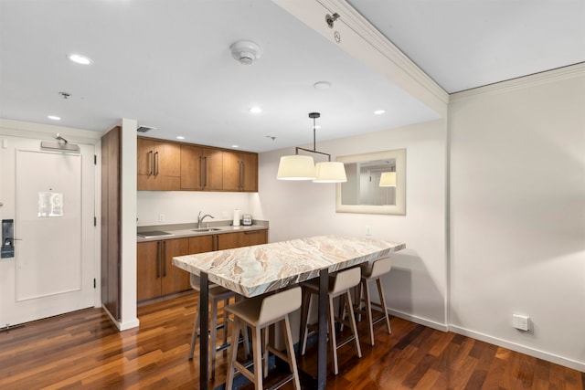 kitchen with kitchen peninsula, dark wood-type flooring, hanging light fixtures, and sink