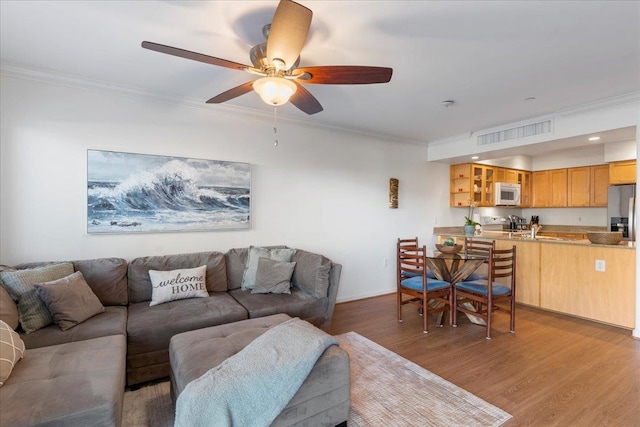 living room with crown molding, ceiling fan, and light hardwood / wood-style floors