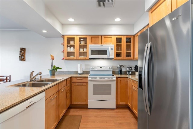 kitchen with sink, kitchen peninsula, white appliances, and light wood-type flooring