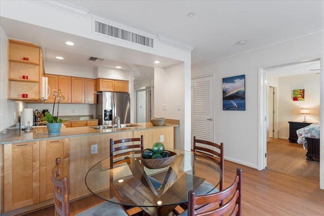 dining space featuring crown molding, sink, and light hardwood / wood-style flooring