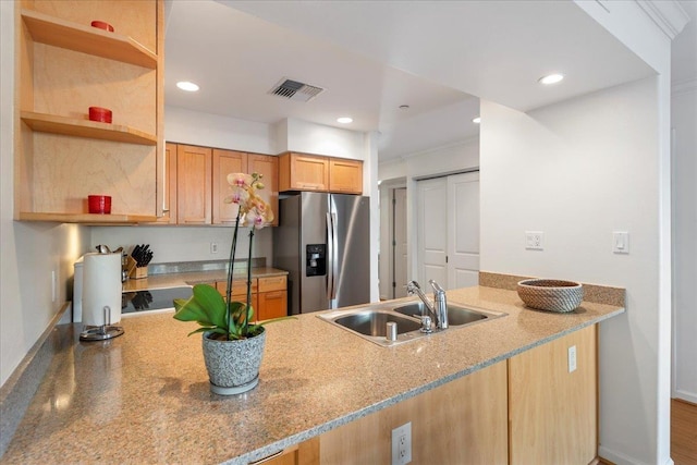 kitchen with stone counters, sink, stainless steel fridge, and kitchen peninsula