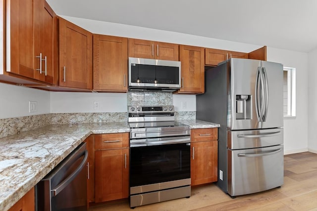 495 Kaiolohia St, Kihei, HI 96753 - kitchen with light stone counters, appliances with stainless steel finishes, brown cabinetry, and light wood-type flooring